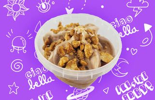 Erdnussbecher Erdnuss Eis, garniert mit knusprigen Nüssen, vor lila Hintergrund mit bunten Mustern.